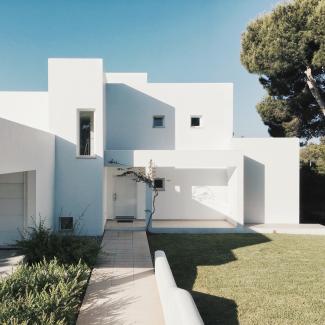 white concrete house near green tree during daytime by Fomstock courtesy of Unsplash.