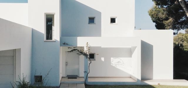 white concrete house near green tree during daytime by Fomstock courtesy of Unsplash.